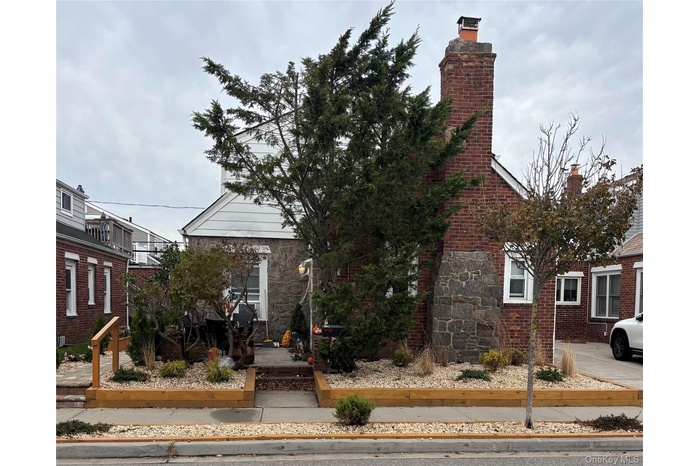 View of front facade with a chimney and stone siding