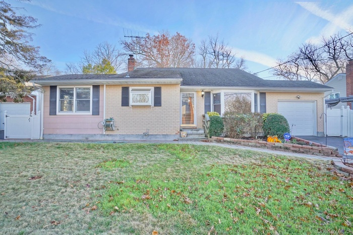 Ranch-style home featuring a gate, an attached garage, a chimney, and brick siding