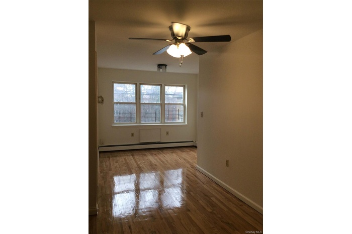 Spare room with light wood-style flooring, baseboard heating, and a ceiling fan
