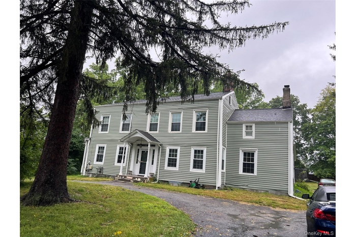 Colonial house featuring a chimney and a front yard