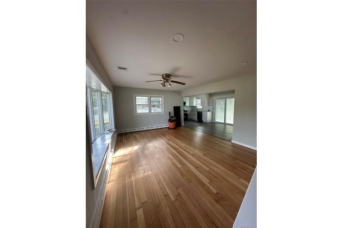 Unfurnished living room with ceiling fan, light wood-style floors, and a baseboard heating unit