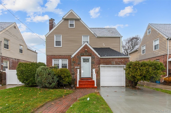 View of front of home with a chimney, brick siding, driveway, and a front yard