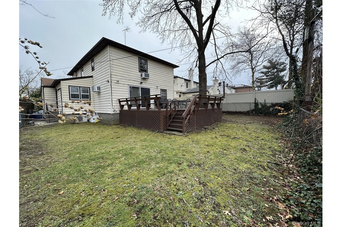 Rear view of house with a wooden deck and stairway