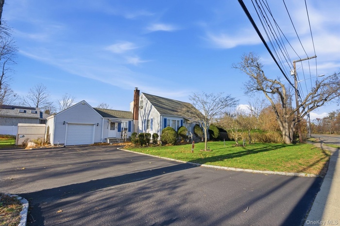 Cape cod house featuring driveway, a front yard, and an attached garage