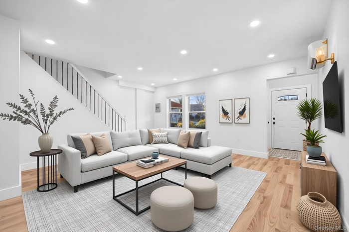 Living room with recessed lighting, light wood-style floors, stairs, and a wall unit AC