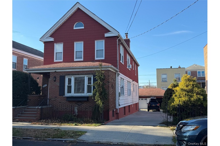 Traditional-style home featuring a chimney, brick siding, and a garage