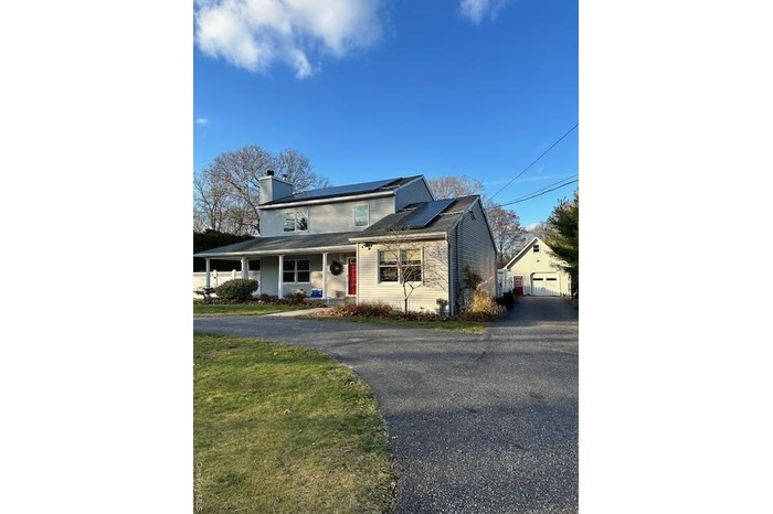 View of front of house featuring an garage , covered porch, front yard, and solar panels