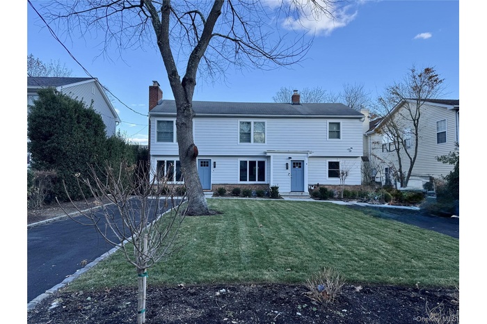 View of front of property featuring a chimney and a front lawn