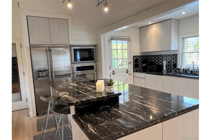 Kitchen has granite counters, and breakfast bar, Electrolux Icon appliances with stainless steel finishes, modern cabinets, and vaulted ceiling
