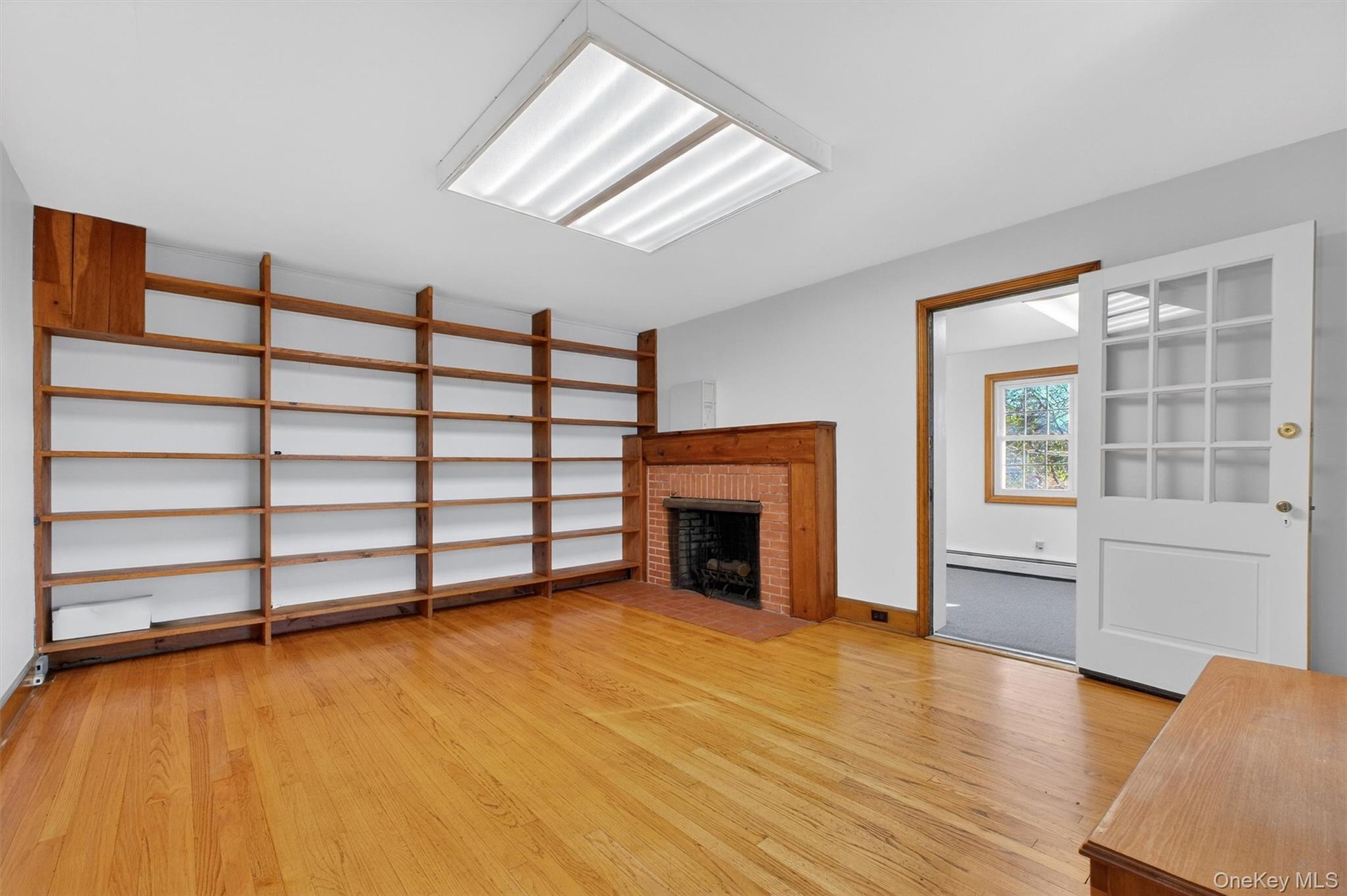 Unfurnished living room with a fireplace, light wood-style floors, and baseboard heating