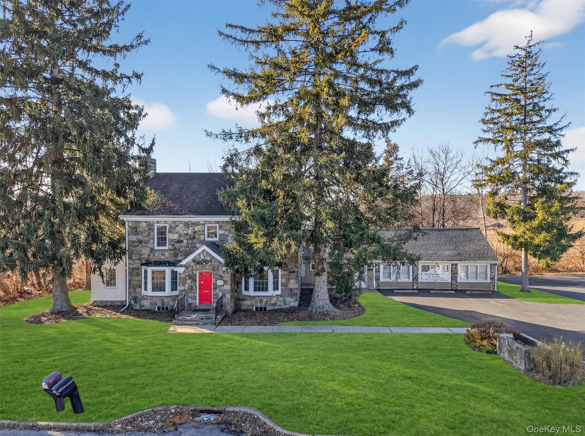 View of front of home featuring stone siding, a front yard, and a chimney