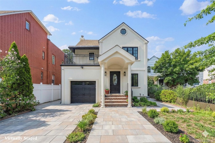 Virtually Staged View of front of property with a balcony, stucco siding, a chimney, and concrete driveway