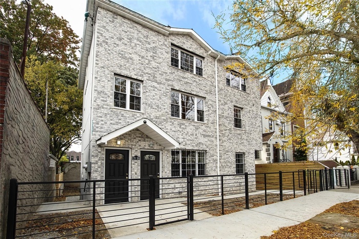 View of front of house with a fenced front yard, a gate, and brick siding