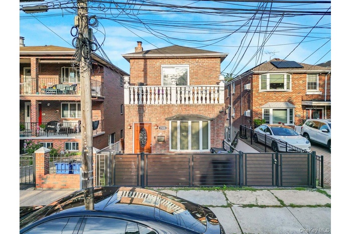 View of front facade featuring brick siding, a gate, a fenced front yard, and a chimney
