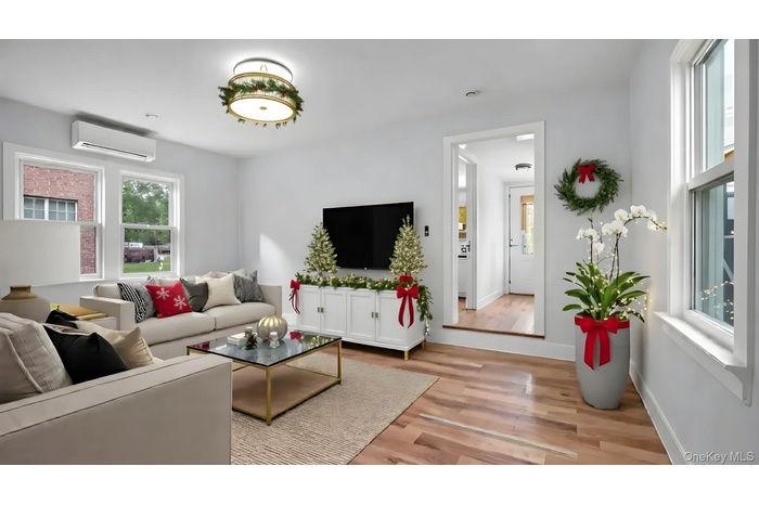 Living room with light wood-style floors and a wall mounted AC