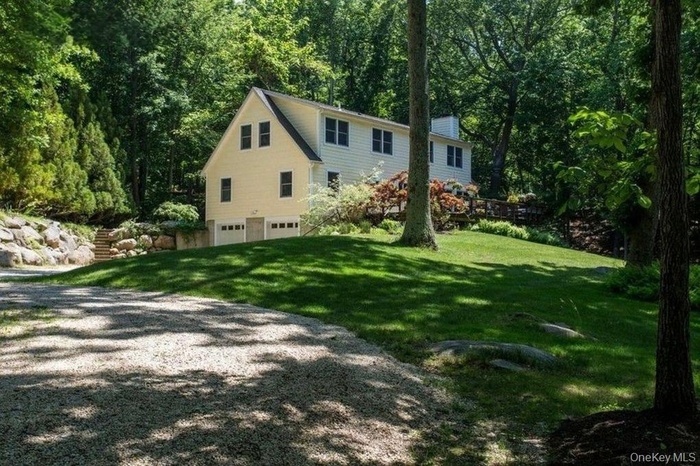 View of side of property with a lawn, driveway, a chimney, and a garage