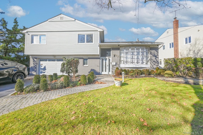 Tri-level home featuring a front yard, an attached garage, and brick siding