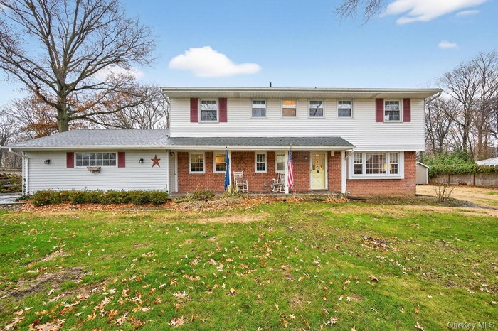 Traditional-style house with covered porch, a front lawn, and brick siding