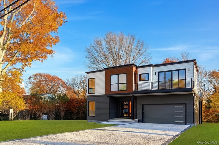Contemporary house featuring a front lawn, gravel driveway, and an attached garage