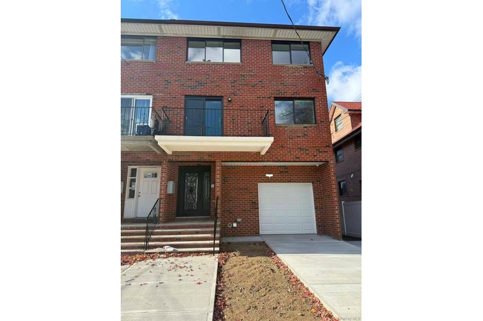 Traditional-style home with brick siding, a balcony, driveway, and a garage