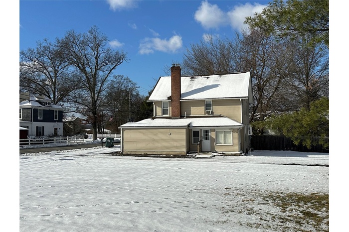 Snow covered rear of property with a chimney