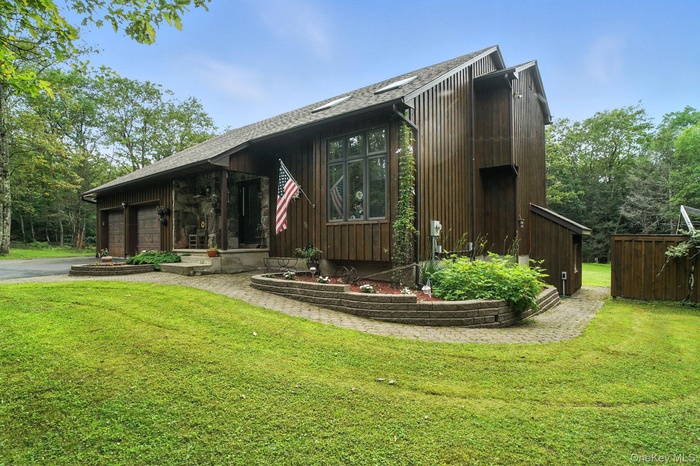 View of front of property featuring a garage, a front lawn, and driveway