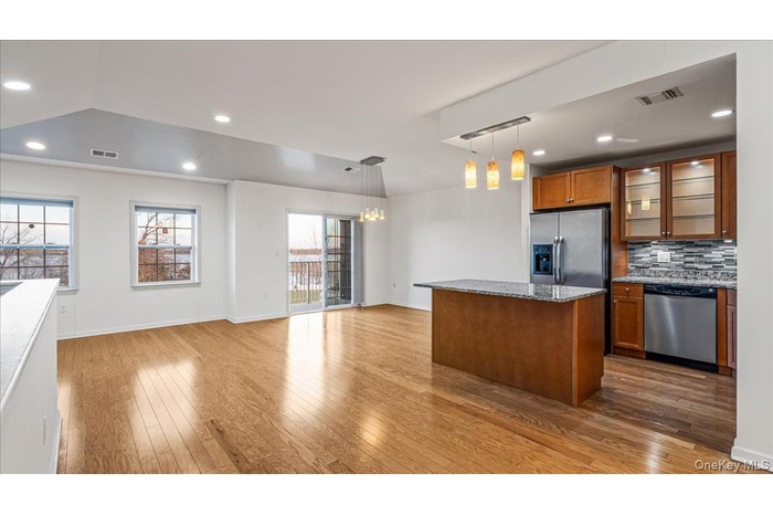 Kitchen featuring brown cabinets, glass insert cabinets, recessed lighting, appliances with stainless steel finishes, and tasteful backsplash