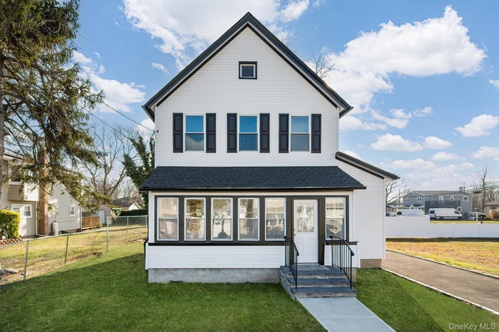 View of front of home featuring a shingled roof and a sunroom