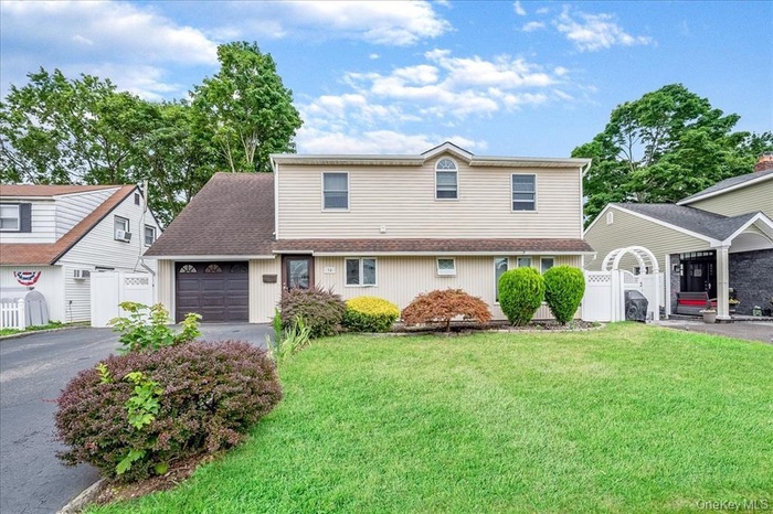 Traditional-style home featuring driveway, a shingled roof, a gate, and an attached garage