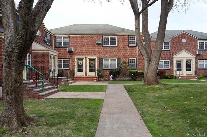 Colonial house with a front lawn, brick siding, and entry steps