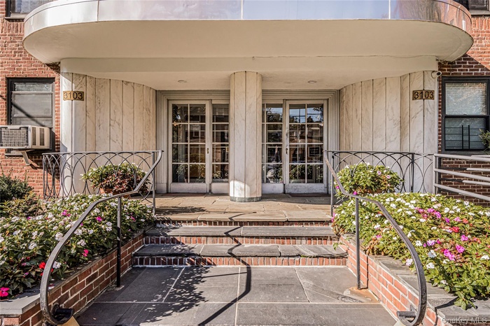Doorway to property with a porch, brick siding, and cooling unit