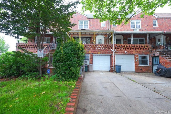 View of front facade with stairway, driveway, and brick siding