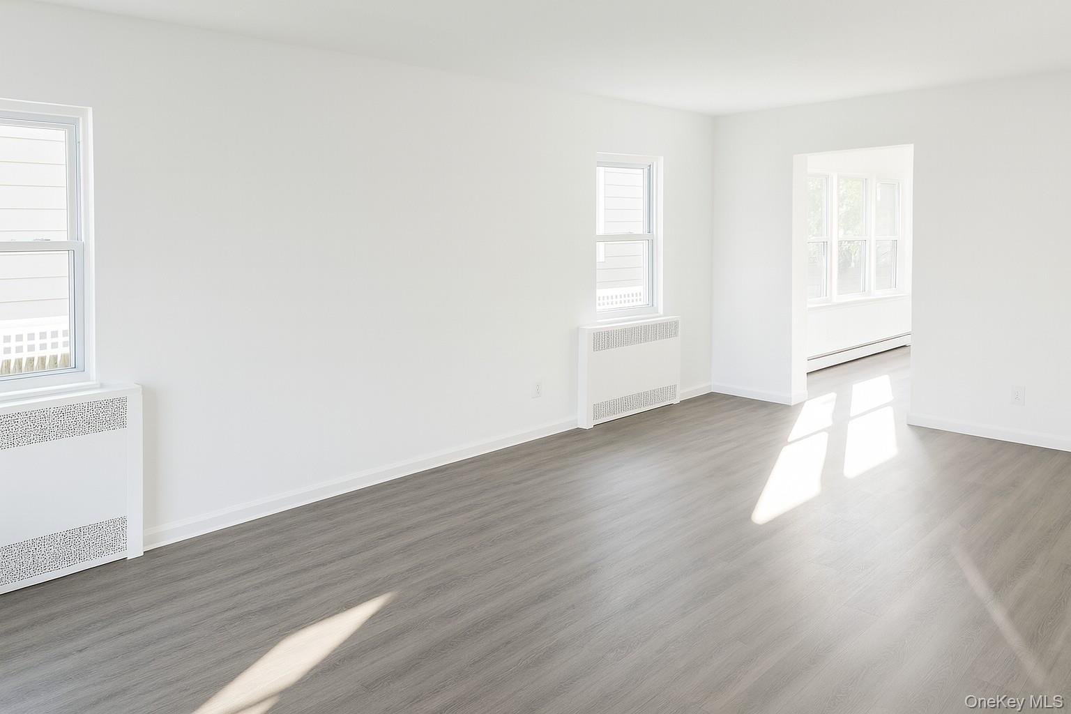 Spare room featuring radiator heating unit, wood finished floors, and a baseboard heating unit