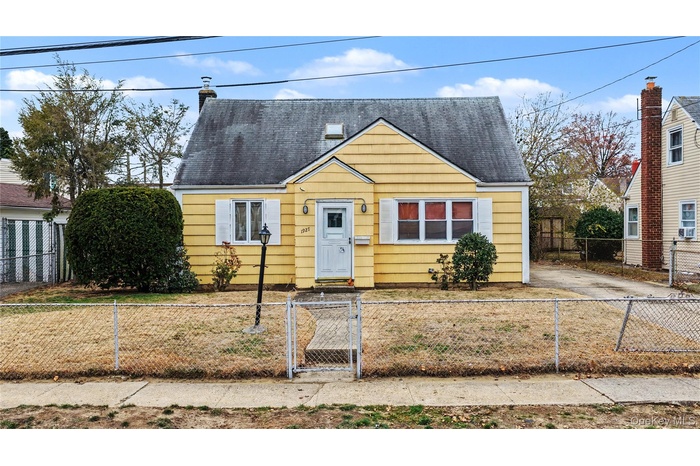 Bungalow-style home with a gate, a shingled roof, and a fenced front yard