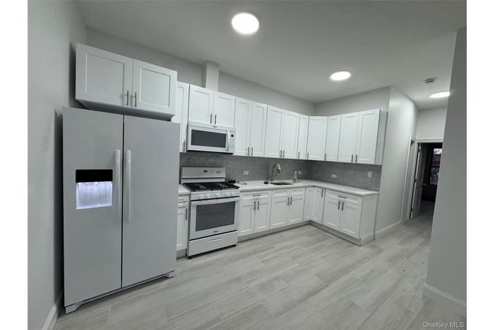 Kitchen featuring white appliances, white cabinetry, and decorative backsplash