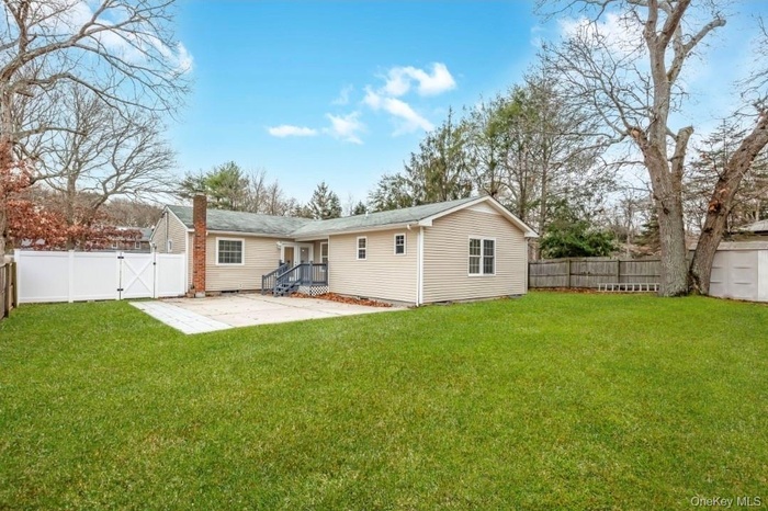Rear view of house with a patio, a gate, a fenced backyard, and a chimney