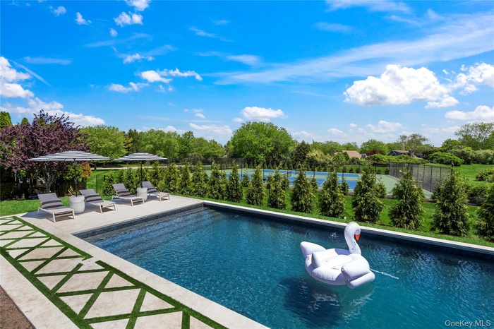 View of swimming pool with a patio and view of wooded area