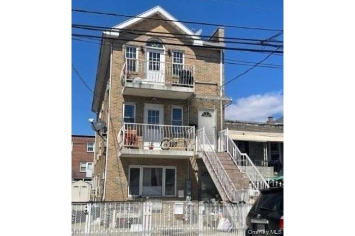 View of front facade featuring a balcony, a fenced front yard, and stairs