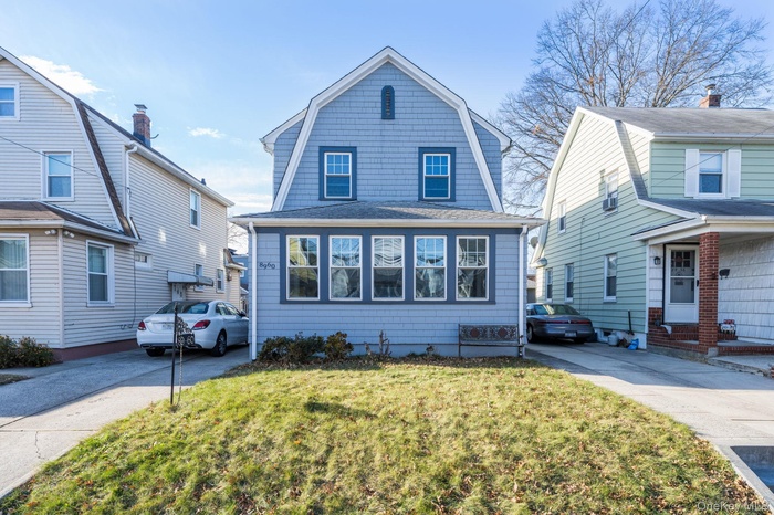 Colonial inspired home with a gambrel roof, a front yard, and a shingled roof