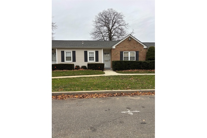 Ranch-style home featuring a front yard, brick siding, and a shingled roof