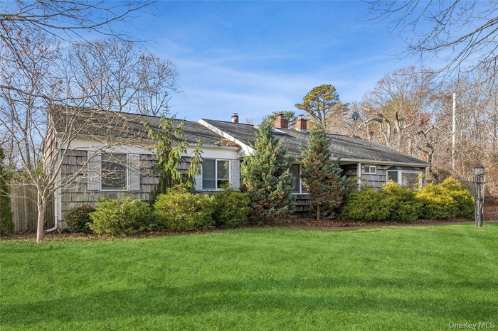 View of front facade featuring a front lawn and a chimney