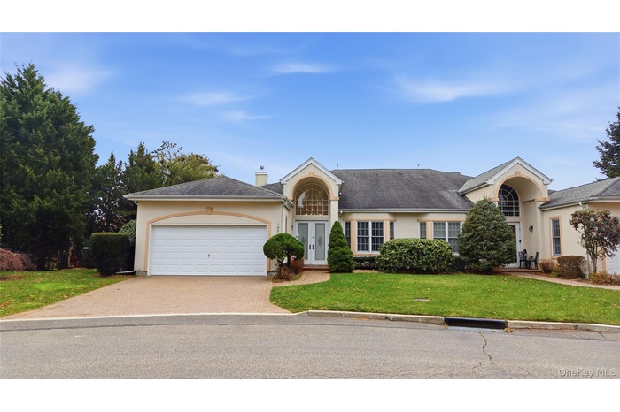 View of front facade with stucco siding, a front yard, driveway and two car garage