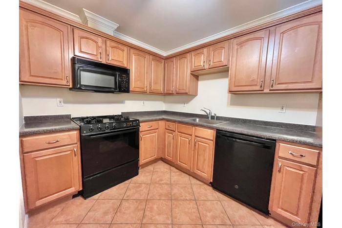 Kitchen with black appliances, dark countertops, and light tile patterned floors