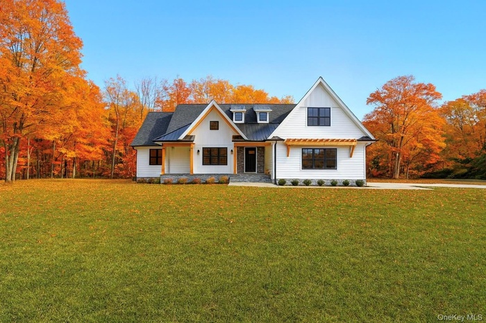 Modern inspired farmhouse featuring covered porch, a front lawn, and a metal roof