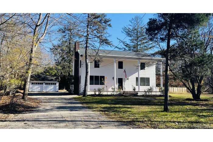 View of front of home with an outdoor structure, covered porch, a chimney, and a garage