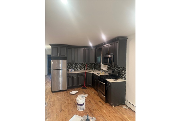 Kitchen featuring stainless steel stove, fridge, backsplash, and light countertops