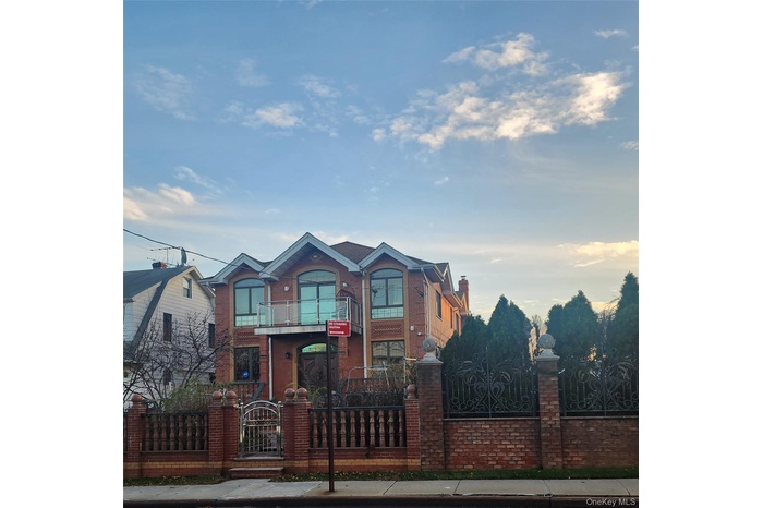 View of front of home featuring a fenced front yard, a gate, brick siding, and a chimney