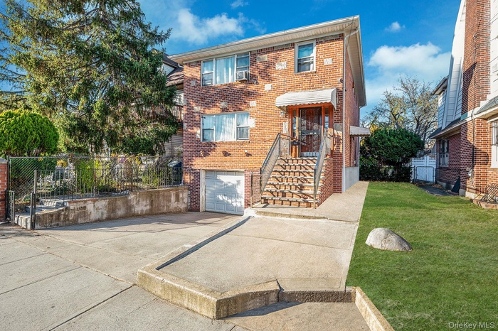 Traditional-style house featuring driveway, brick siding, and a garage