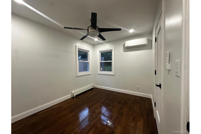 Unfurnished room with a baseboard radiator, dark wood-style flooring, a wall mounted air conditioner, a ceiling fan, and recessed lighting