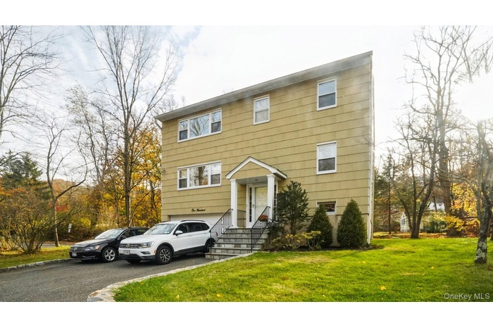 View of front of house with asphalt driveway, a garage, and a front lawn